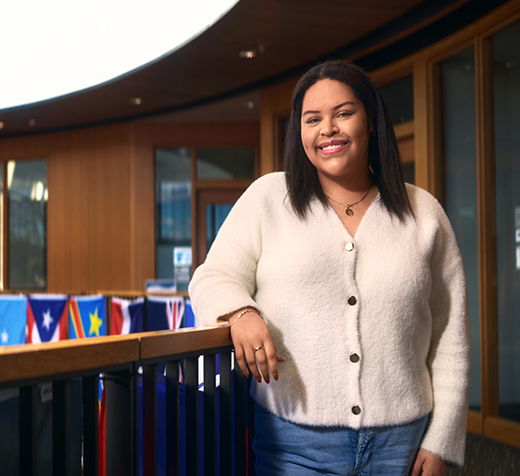 A woman stands with her arms crossed next to a window